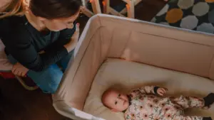 Une mère veille son bébé couché dans un berceau près d'elle