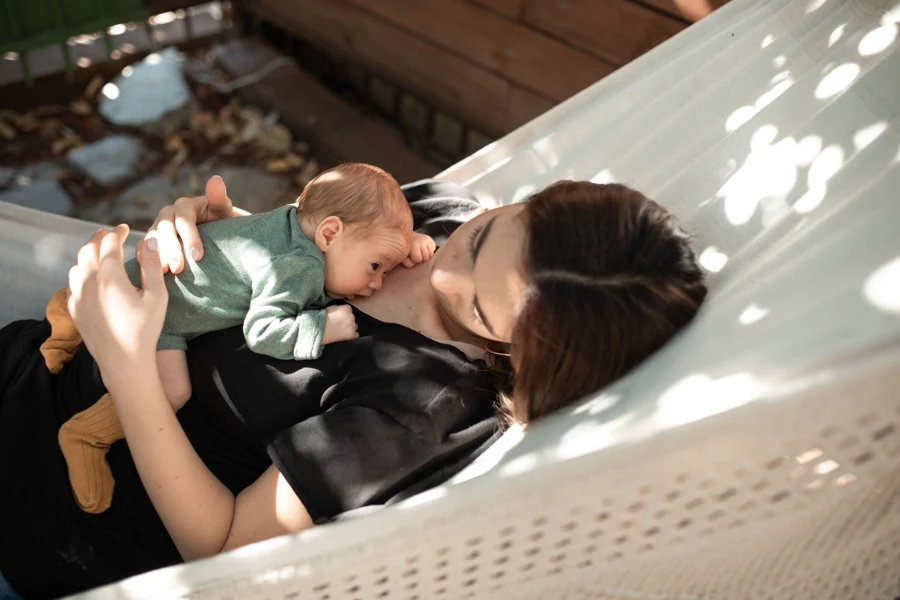 Mère allongée dans un hamac avec son nourrisson contre elle
